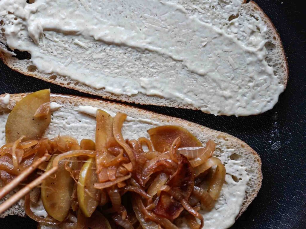 adding apple onion mixture to bread on pan